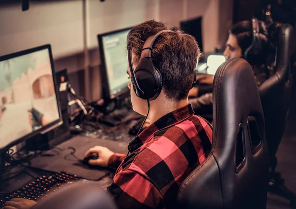 A player headphones-on in a leather racing chair at a single station, cabin-quiet